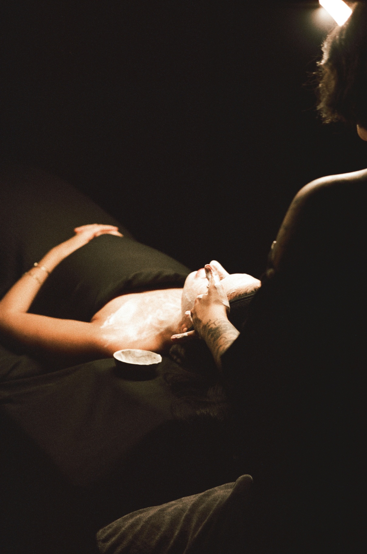 Cream mask being applied to a client's arm under warm lamp light